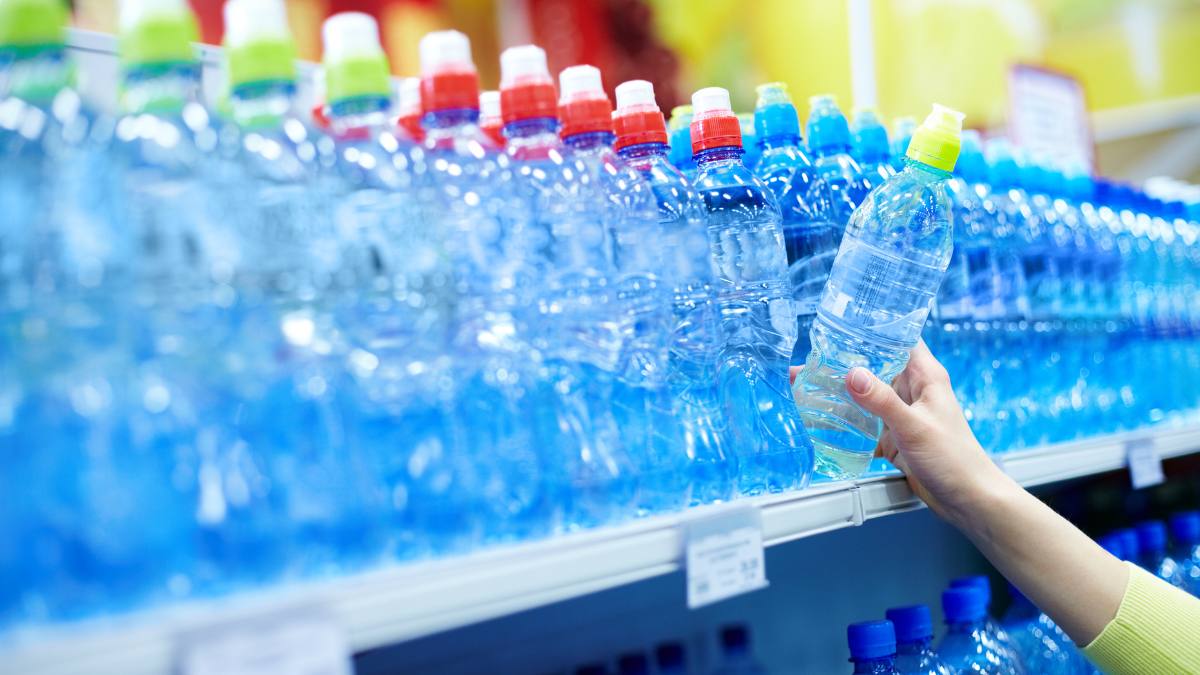 Experții au testat apa din supermarketuri. În imagine, o mână alege o sticlă de apă în supermarket