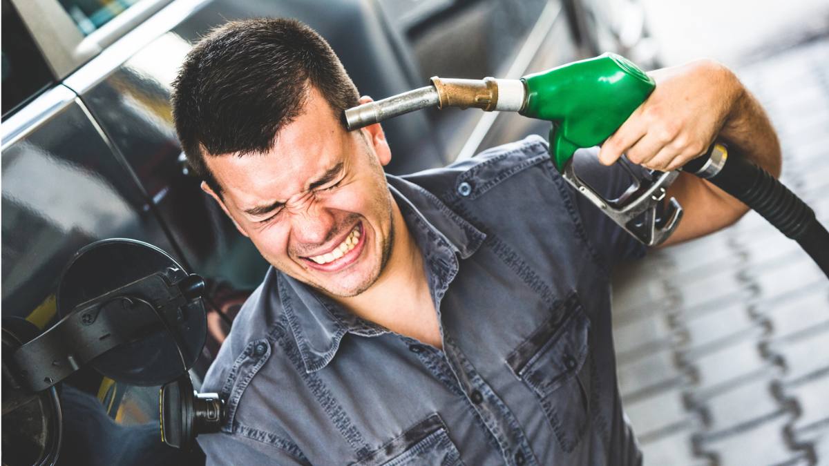 Motorina se scumpește puternic Germania. În imagine, un șofer cu pompa de carburant la tâmplă