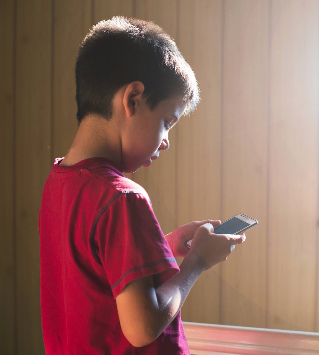 vârsta minimă rețele sociale UE. În imagine, un copil care ține un telefonul în mâini