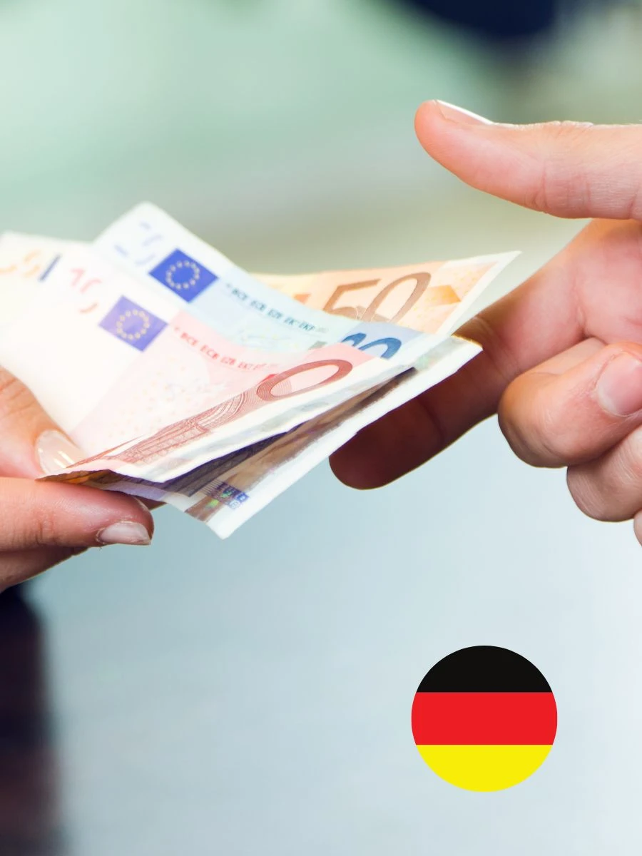 Germania majorează salariile minime pentru lucrătorii temporari. Imagine ilustrativă cu înmânarea unei sume de bani în euro și culorile Germaniei
