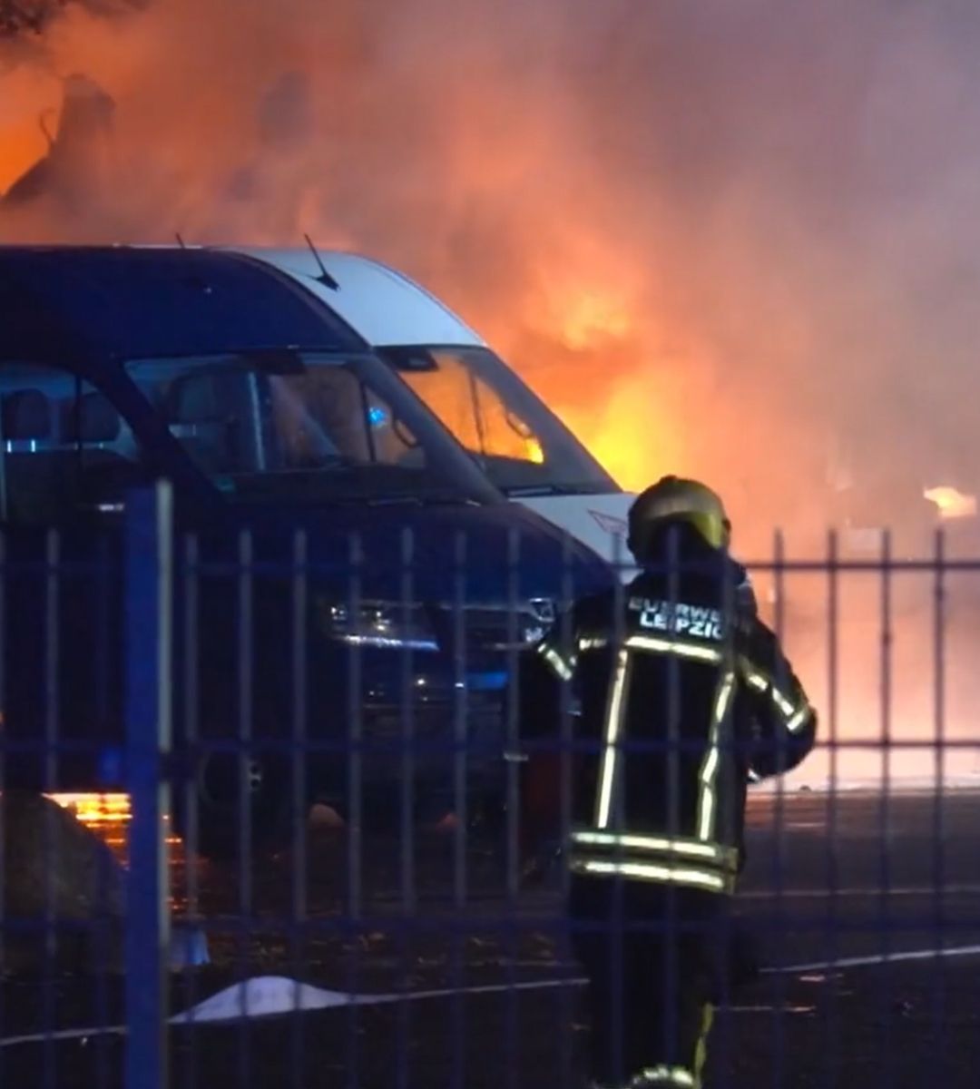 Pompier din Leipzig intervenind lângă autoutilitare cuprinse de flăcări la centrul MAN