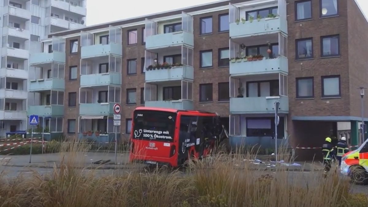 Autobuz roșu intrat în fațada unui bloc de locuințe din Bad Oldesloe, lângă echipajele de intervenție