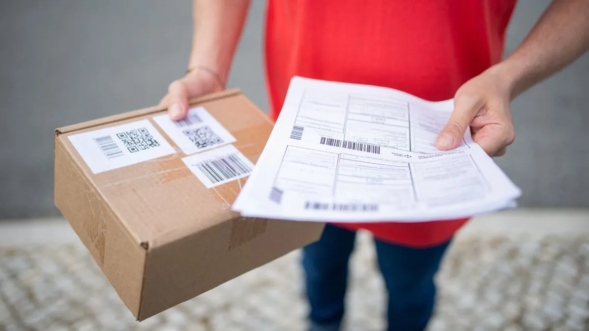 Persoană ținând un colet din carton și documente de expediere, imagine ilustrativă pentru comenzile online