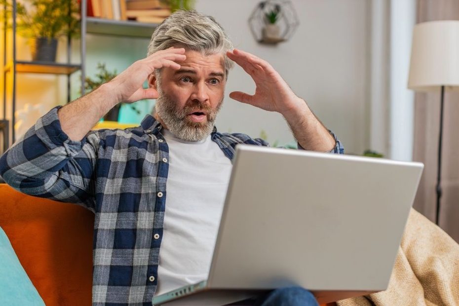 Bărbat surprins și îngrijorat în fața unui laptop, imagine ilustrativă pentru noile reguli privind conturile bancare din străinătate, aplicabile din ianuarie 2027.