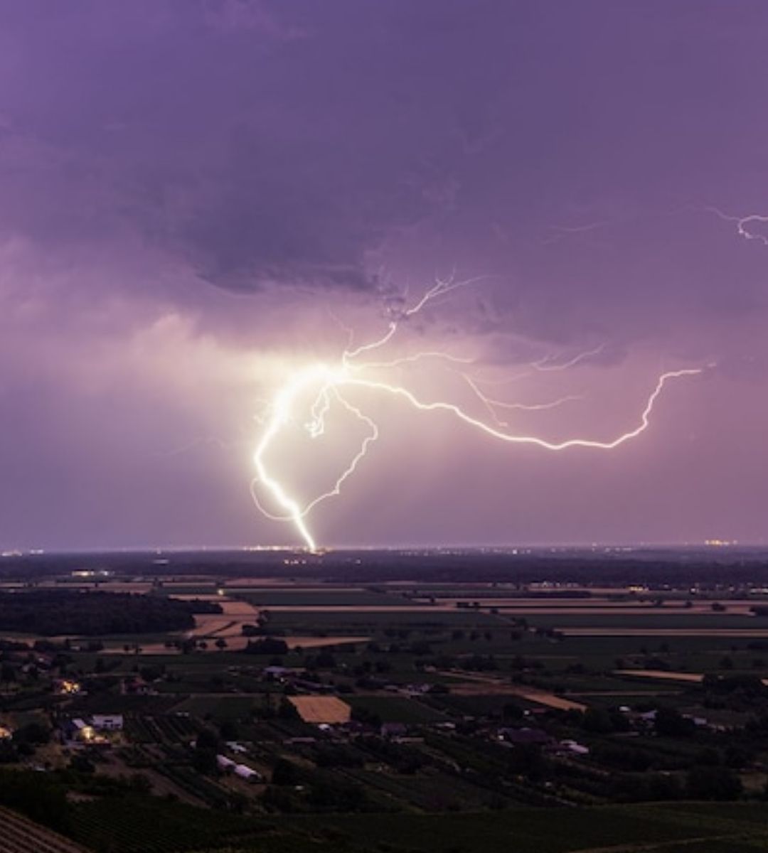 Furtună puternică în Germania – fulgere spectaculoase luminează cerul violet deasupra unei zone rurale, în timpul unui episod de vreme severă. Imagine ilustrativă.