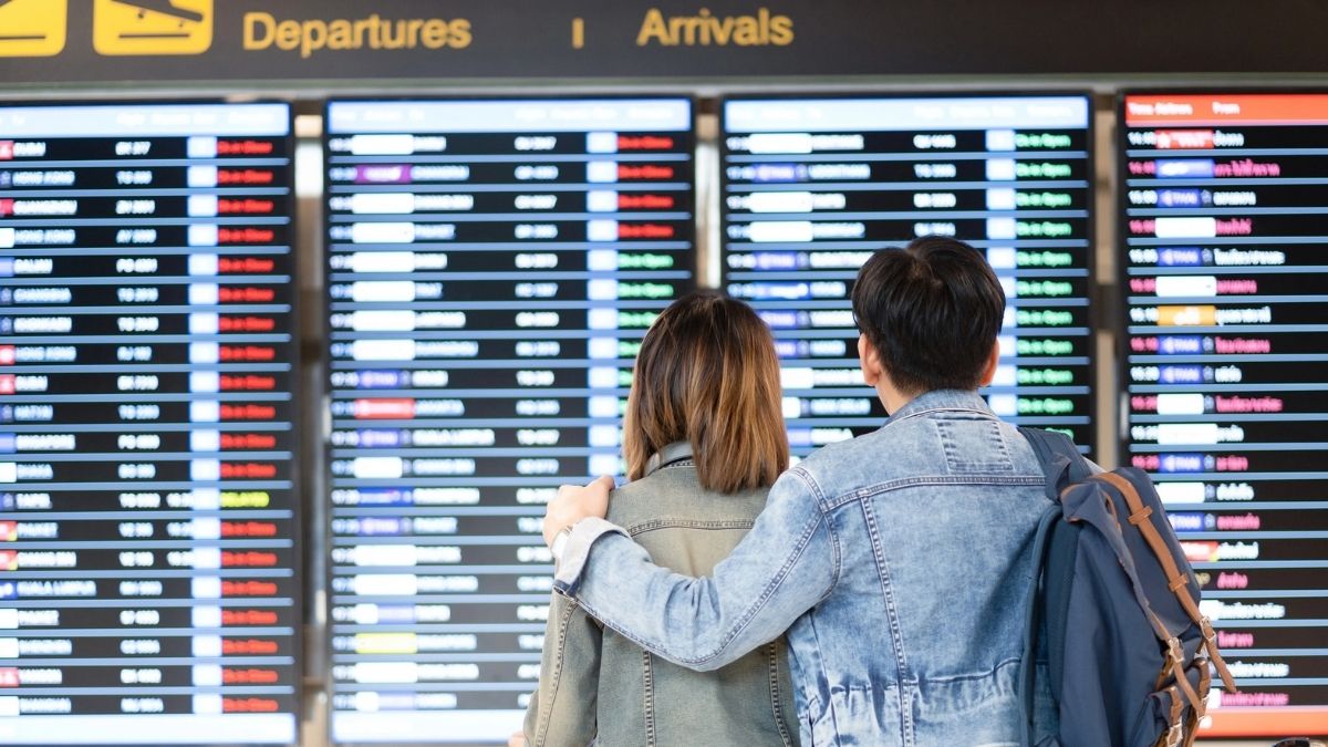 Pasageri într-un aeroport, în fața panourilor de plecări și sosiri – noile drepturi pentru călătoriile cu avionul în UE