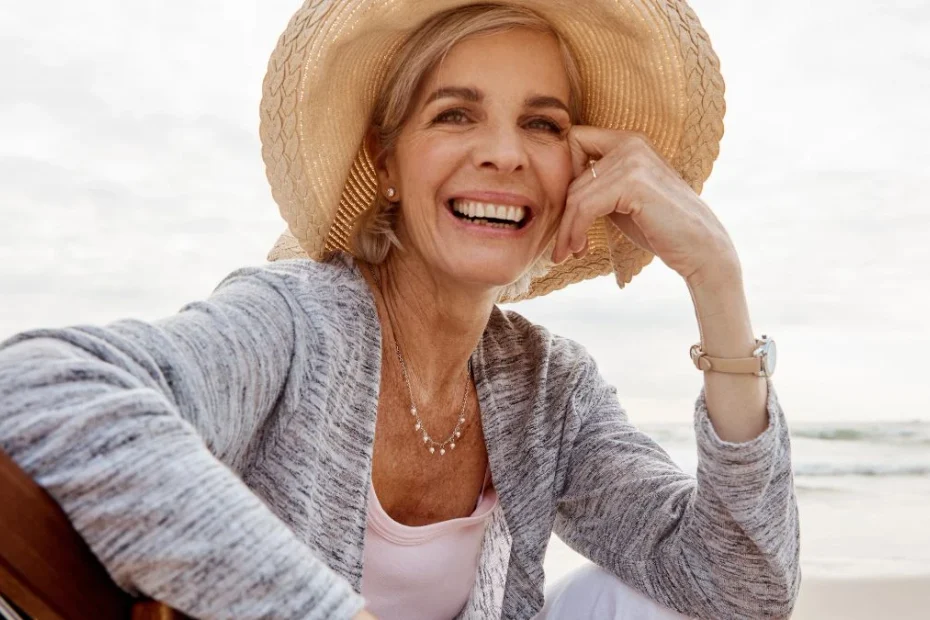 Femeie pensionară zâmbitoare, cu pălărie de paie, relaxându-se pe malul mării, imagine ilustrativă pentru cele mai bune țări în care să trăiești la pensie în 2026.