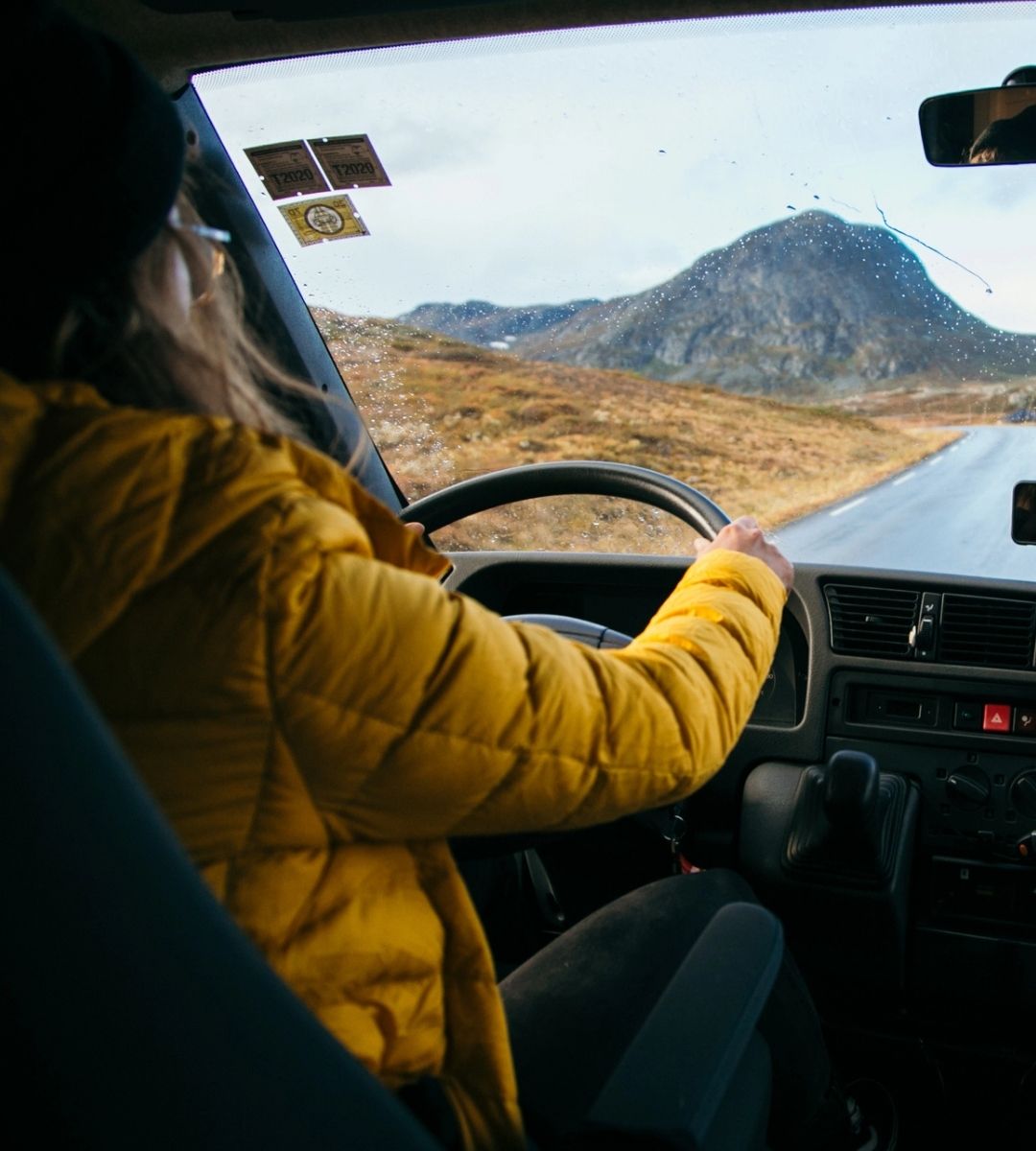 Permis categoria B pentru vehicule de până la 4,25 tone – femeie la volanul unei autoutilitare, pe un drum de munte, imagine ilustrativă.
