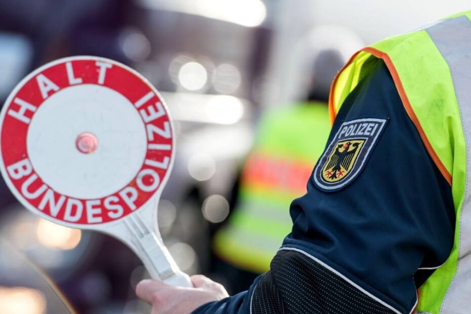 Polițist federal german cu vestă reflectorizantă și paletă de oprire „Halt Bundespolizei”, fotografie ilustrativă