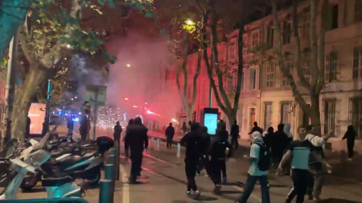 Grupuri de persoane pe o stradă noaptea, printre fum și lumini roșii, în timpul protestelor