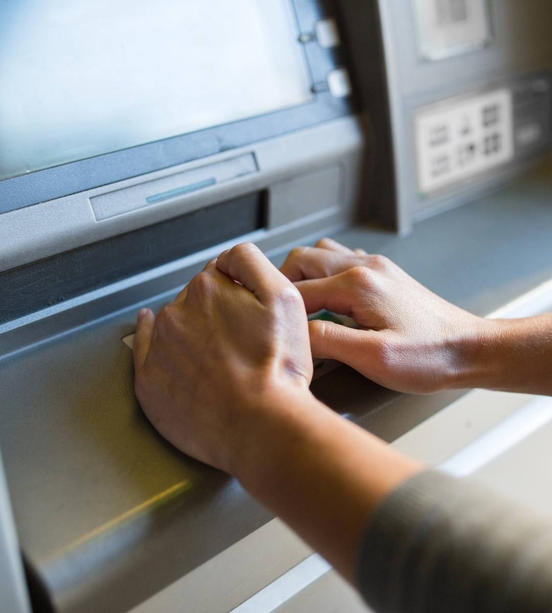 Persoană care folosește tastatura unui bancomat pentru o operațiune bancară, imagine ilustrativă