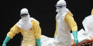 Epidemia de Ebola se agravează. În imagine, personal sanitar în costume de protecție transportă o persoană infectată