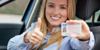 Tânără la volan care arată un permis de conducere, imagine ilustrativă